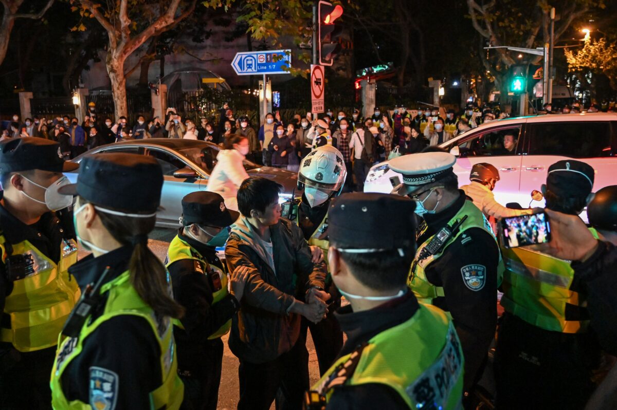 Các sĩ quan cảnh sát đối đầu với một người đàn ông khi họ chặn đường Wulumuqi ở Thượng Hải hôm 27/11/2022. (Ảnh: Hector Retamal/AFP qua Getty Images)