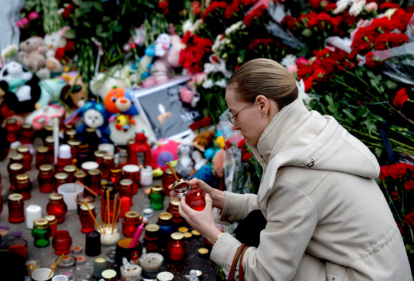 Một người phụ nữ thắp nến tại đài tưởng niệm các nạn nhân của vụ xả súng tại địa điểm tổ chức buổi hòa nhạc Crocus City Hall gần Moscow hôm 24/03/2024. (Ảnh: Maxim Shemetov/Reuters)